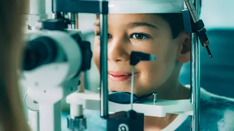 Niño sometiéndose a un examen oftalmológico Niño sometiéndose a un examen oftalmológico