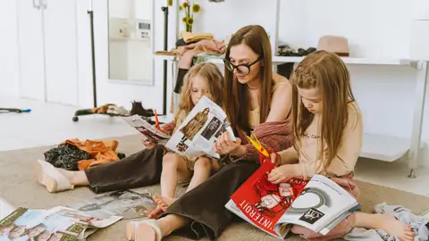 Una madre junto a sus hijas mirando revistas Una madre junto a sus hijas mirando revistas