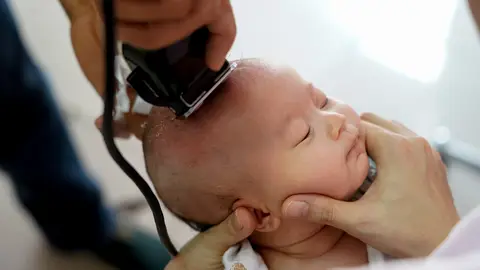 Corte de pelo con máquina a un bebé recién nacido Corte de pelo con máquina a un bebé recién nacido