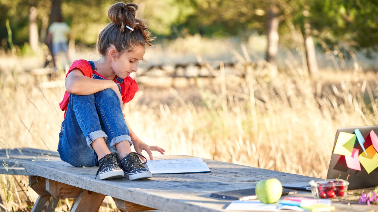 Ni&ntilde;a leyendo en el campo