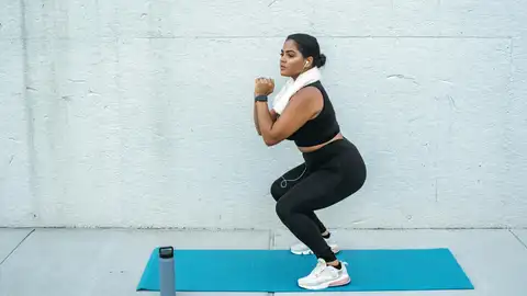 Mujer practicando un ejercicio isométrico: la sentadilla Mujer practicando un ejercicio isométrico: la sentadilla