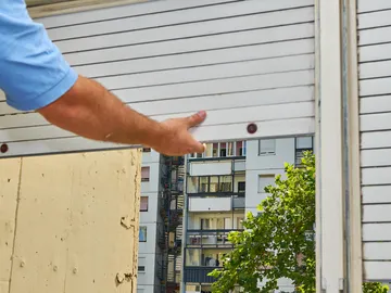 Hombre subiendo persiana Hombre subiendo persiana