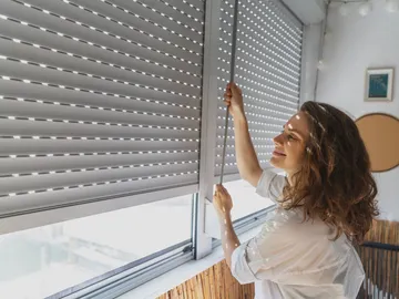 Mujer subiendo una persiana Mujer subiendo una persiana