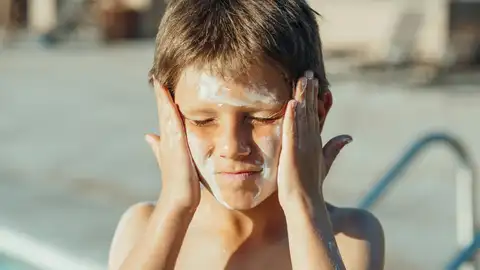Niño poniéndose protector solar Niño poniéndose protector solar
