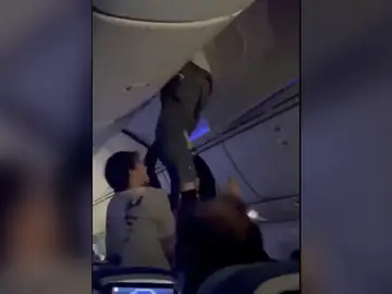 Un pasajero intentando salir del compartimento de las maletas Un pasajero intentando salir del compartimento de las maletas