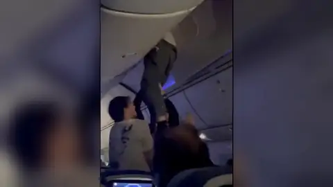 Un pasajero intentando salir del compartimento de las maletas