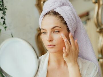 Una mujer se aplica en el rostro productos cosméticos