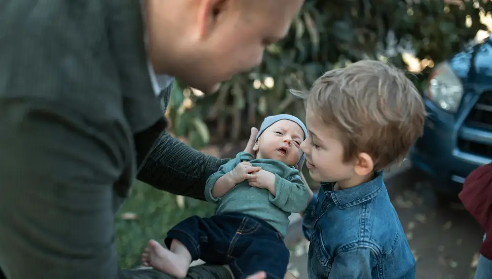 Un padre le enseña el nuevo hermanito al hijo mayor Un padre le enseña el nuevo hermanito al hijo mayor