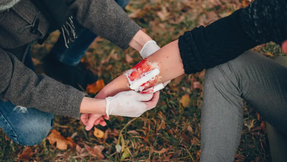 Una persona cura una herida de una señora Una persona cura una herida de una señora