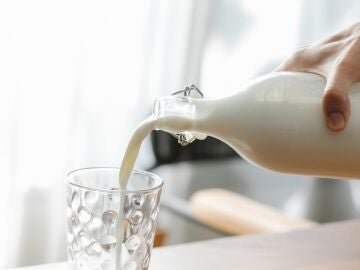 Una persona sirviendo un vaso de leche