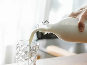 Una persona sirviendo un vaso de leche Una persona sirviendo un vaso de leche