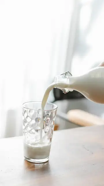 Una persona sirviendo un vaso de leche Una persona sirviendo un vaso de leche
