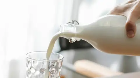 Una persona sirviendo un vaso de leche Una persona sirviendo un vaso de leche