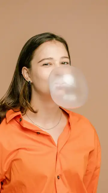 Una persona haciendo una pompa con un chicle Una persona haciendo una pompa con un chicle