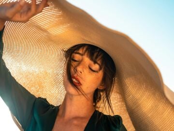 Mujer expuesta al sol y protegida por un gran sombrero