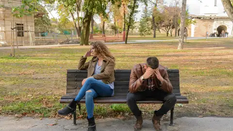 Una pareja discute en un banco del parque Una pareja discute en un banco del parque