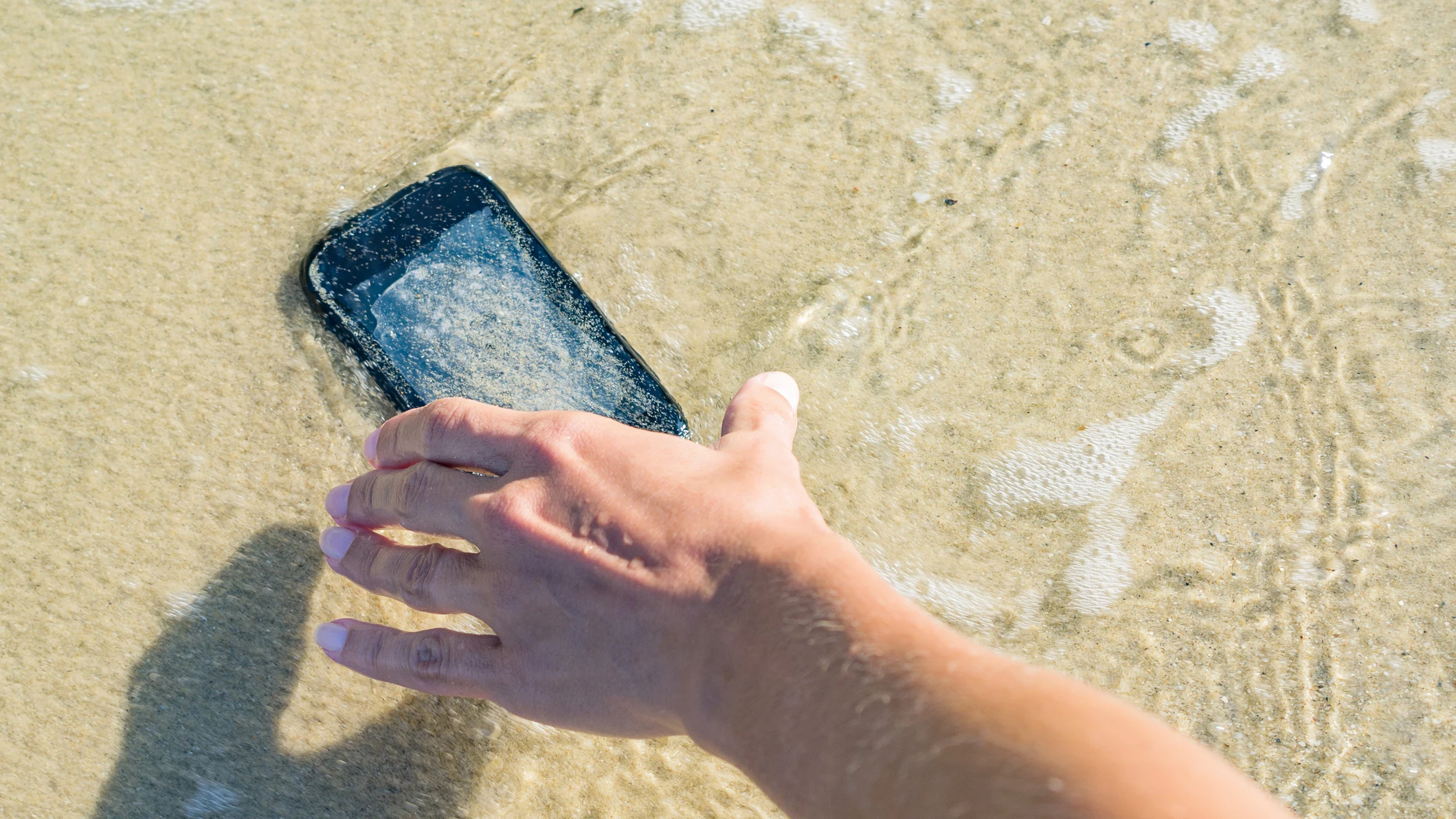 Un móvil en el agua de la playa Un móvil en el agua de la playa