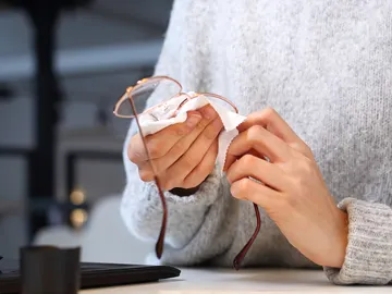 Una persona limpiando sus gafas Una persona limpiando sus gafas