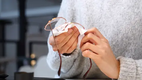 Una persona limpiando sus gafas Una persona limpiando sus gafas