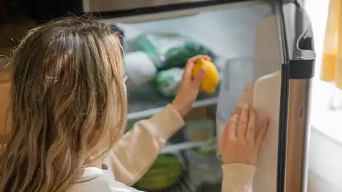 Una mujer colocando la nevera Una mujer colocando la nevera