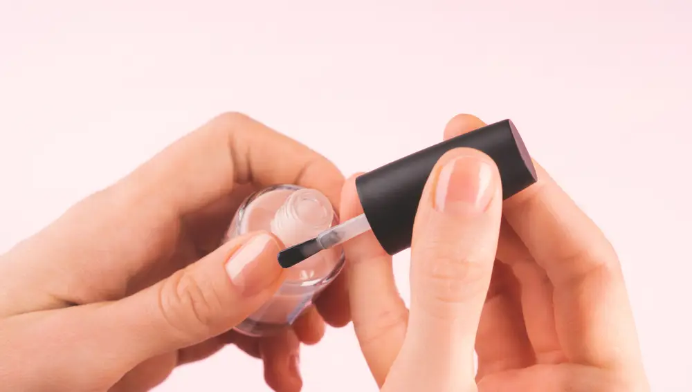 Una persona aplicando esmalte transparente Una persona aplicando esmalte transparente