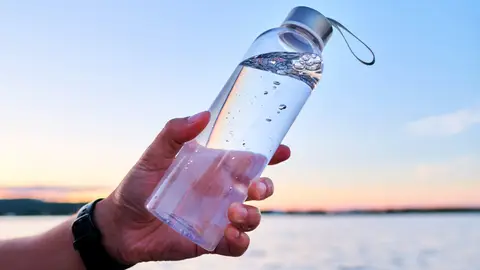Una botella de vidrio que contiene agua Una botella de vidrio que contiene agua