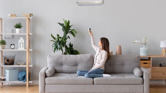 Una mujer poniendo el aire acondicionado en su sal&oacute;n