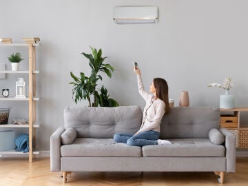 Una mujer poniendo el aire acondicionado en su salón