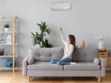Una mujer poniendo el aire acondicionado en su salón Una mujer poniendo el aire acondicionado en su salón