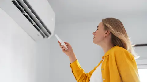 Una mujer refrescándose con el aire acondicionado Una mujer refrescándose con el aire acondicionado