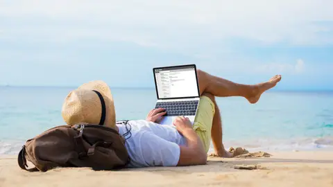 Un hombre trabaja desde la playa Un hombre trabaja desde la playa