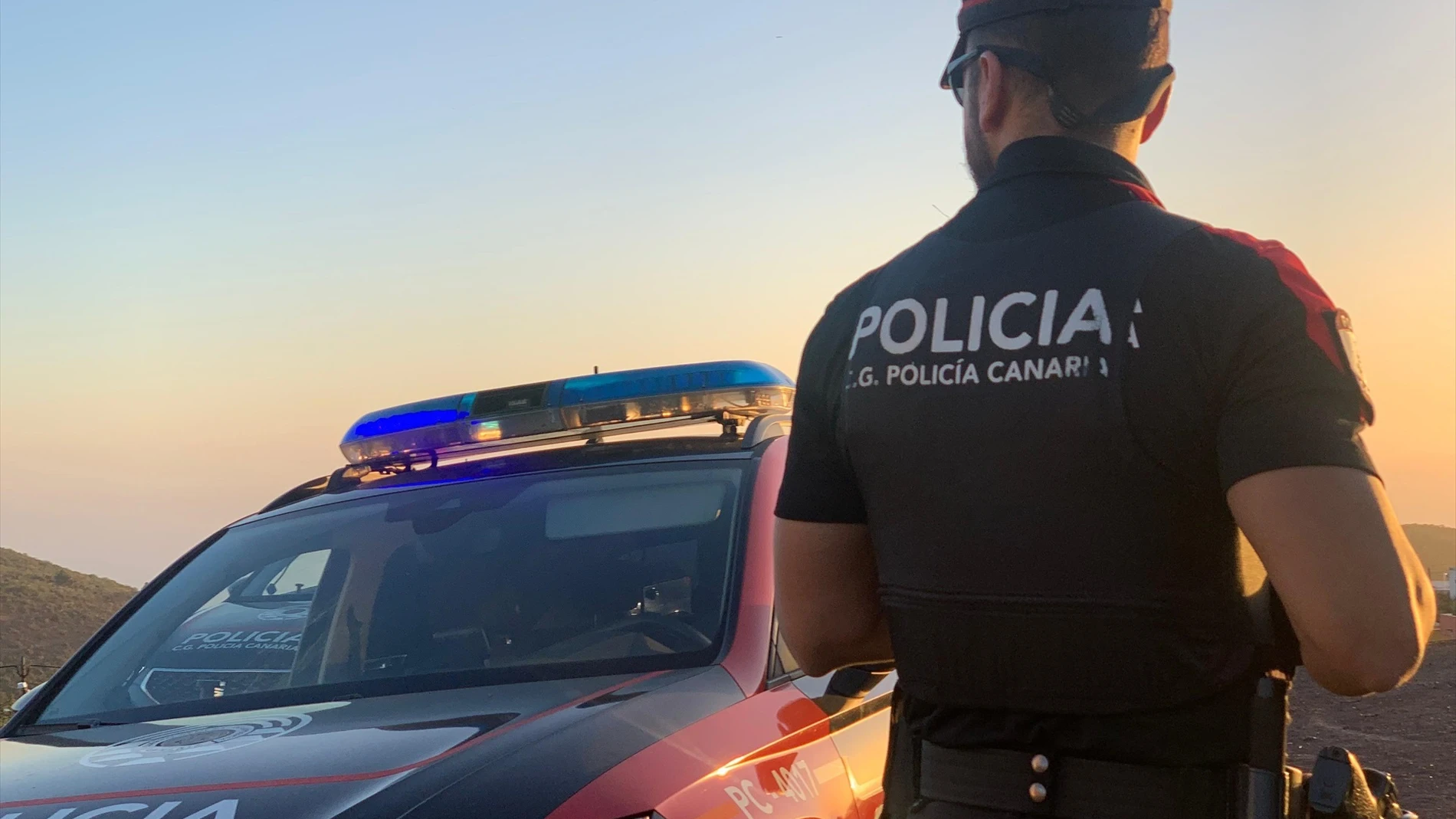 Agente de la Policía Canaria junto a un coche patrulla Agente de la Policía Canaria junto a un coche patrulla