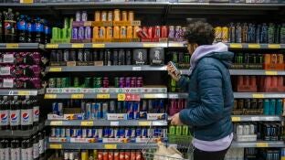 Un joven mira la secci&oacute;n de bebidas energ&eacute;ticas en el supermercado