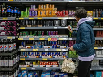 Un joven mira la sección de bebidas energéticas en el supermercado Un joven mira la sección de bebidas energéticas en el supermercado