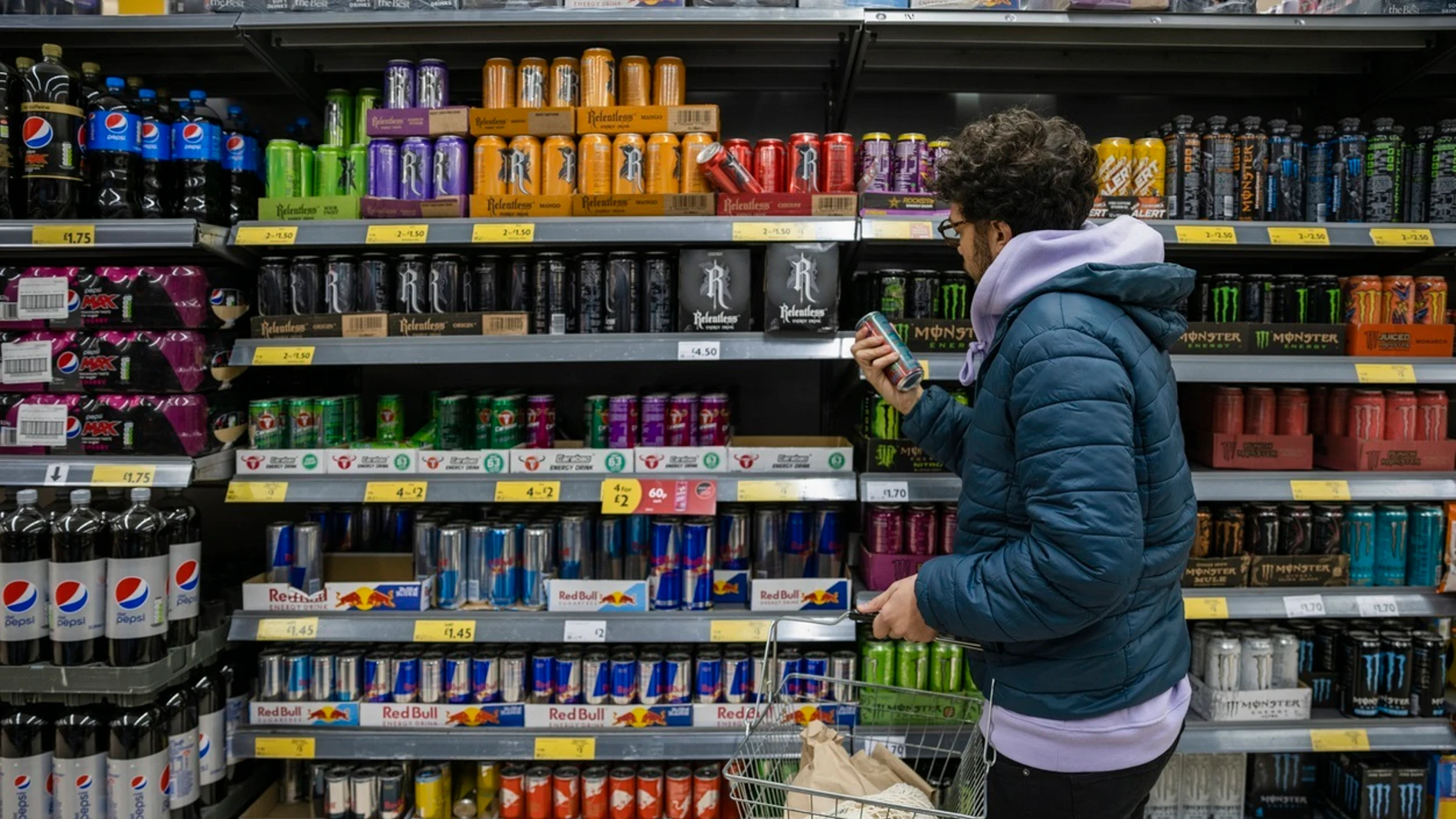 Un joven mira la sección de bebidas energéticas en el supermercado Un joven mira la sección de bebidas energéticas en el supermercado