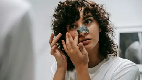 Una mujer con un parche en la nariz para tratar los puntos negros Una mujer con un parche en la nariz para tratar los puntos negros