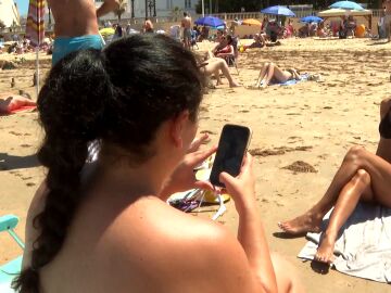 Mujer mirando el móvil en la playa