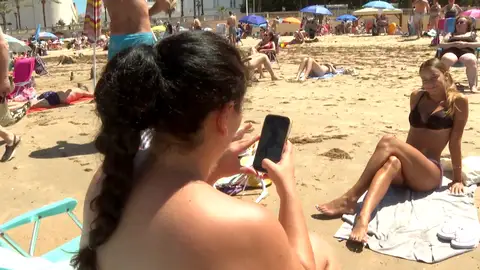 Mujer mirando el móvil en la playa Mujer mirando el móvil en la playa