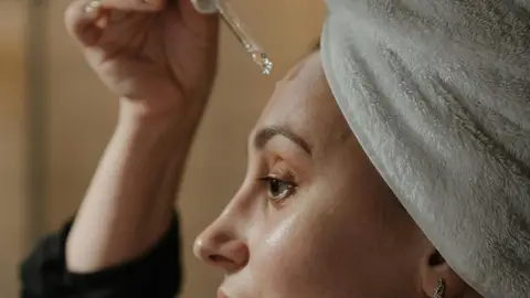 Mujer aplicándose un aceite Mujer aplicándose un aceite