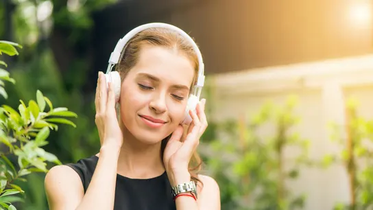 Una mujer escucha música a través de los auriculares Una mujer escucha música a través de los auriculares