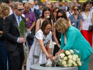 Varias personas participan en una ofrenda floral durante el acto en homenaje a las víctimas del atentado