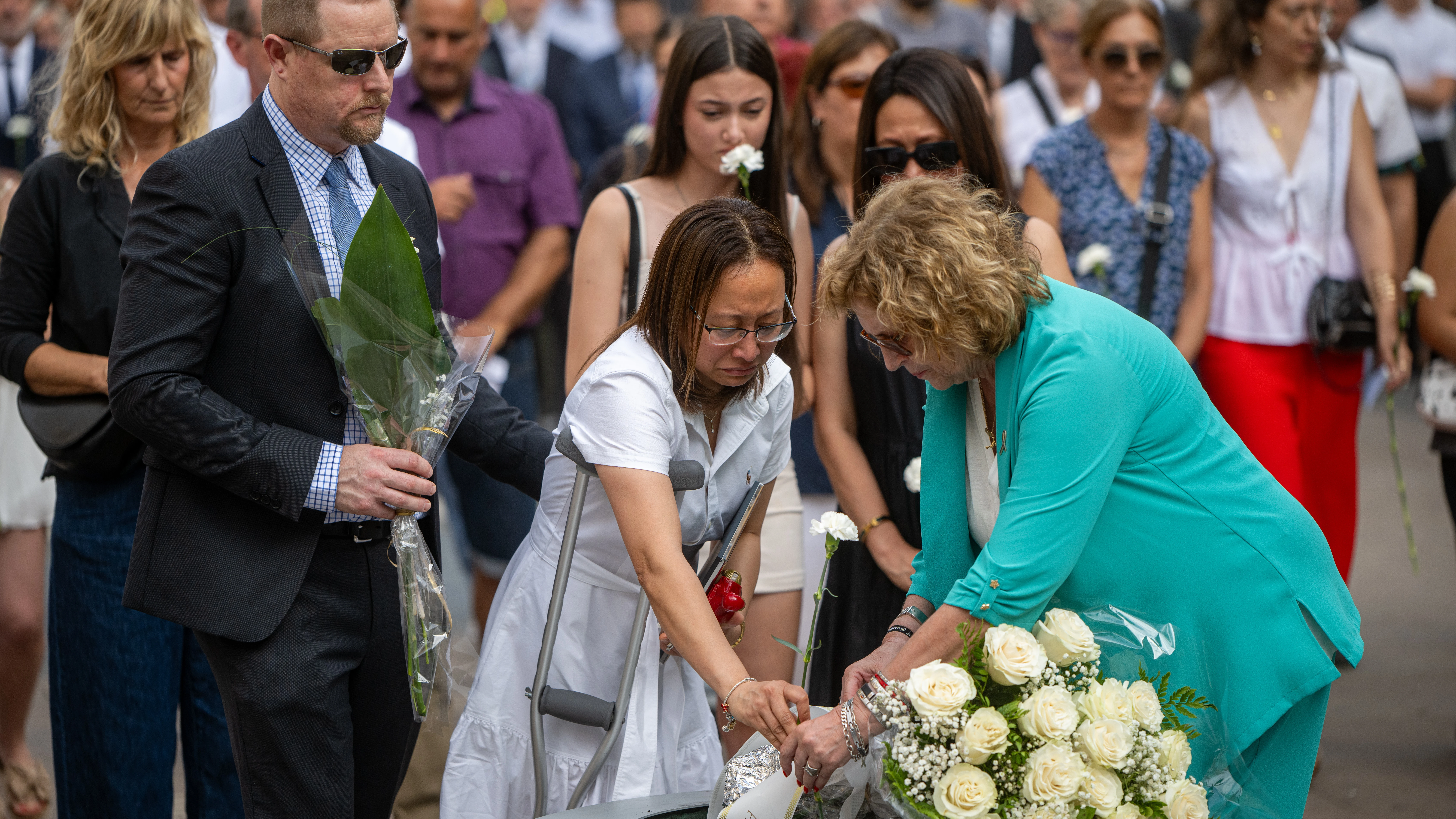 Varias personas participan en una ofrenda floral durante el acto en homenaje a las v&iacute;ctimas del atentado