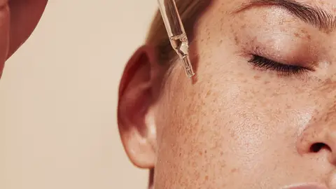 Mujer bronceada aplicándose retinol Mujer bronceada aplicándose retinol