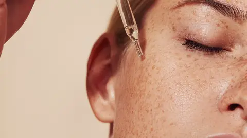 Mujer bronceada aplicándose retinol Mujer bronceada aplicándose retinol