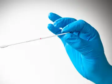 Mano con guante de látex sosteniendo hisopo Mano con guante de látex sosteniendo hisopo