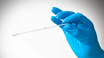 Mano con guante de látex sosteniendo hisopo Mano con guante de látex sosteniendo hisopo