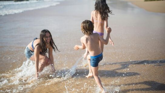 Ni&ntilde;as y ni&ntilde;o jugando en la orilla de la playa