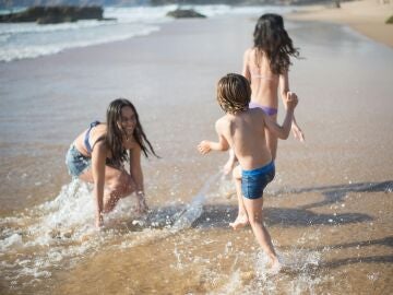 Niñas y niño jugando en la orilla de la playa