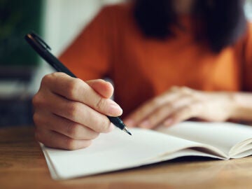 Mujer escribiendo a mano en un cuaderno