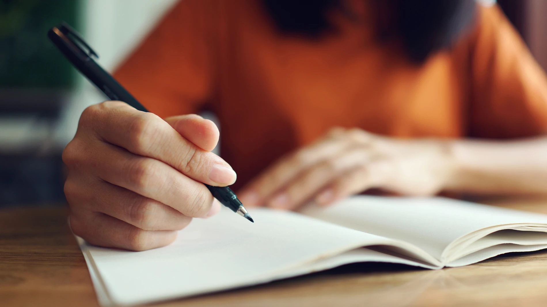 Mujer escribiendo a mano en un cuaderno Mujer escribiendo a mano en un cuaderno